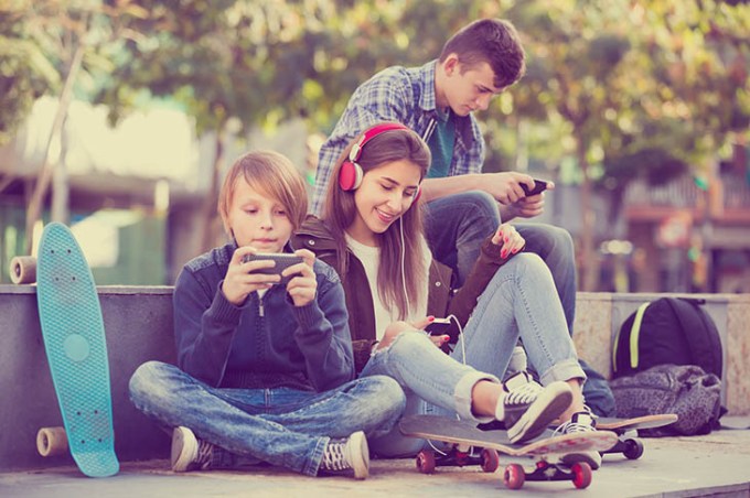 Three teenagers with phones outdoors